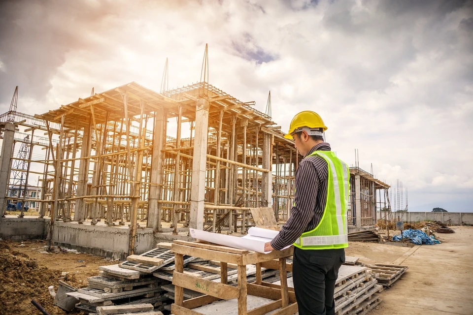 jeune homme d'affaires ingénieur professionnel sur le chantier de construction de l'immeuble à la maison avec un plan