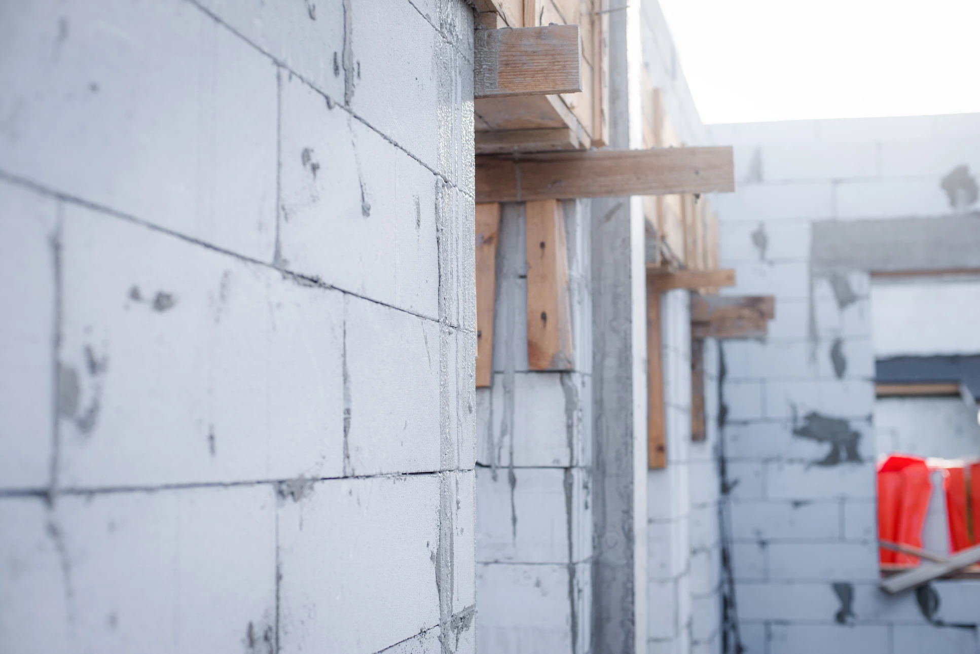 Chantier de construction en extérieur avec ouvriers en gilets de sécurité orange travaillant sur structure béton armé