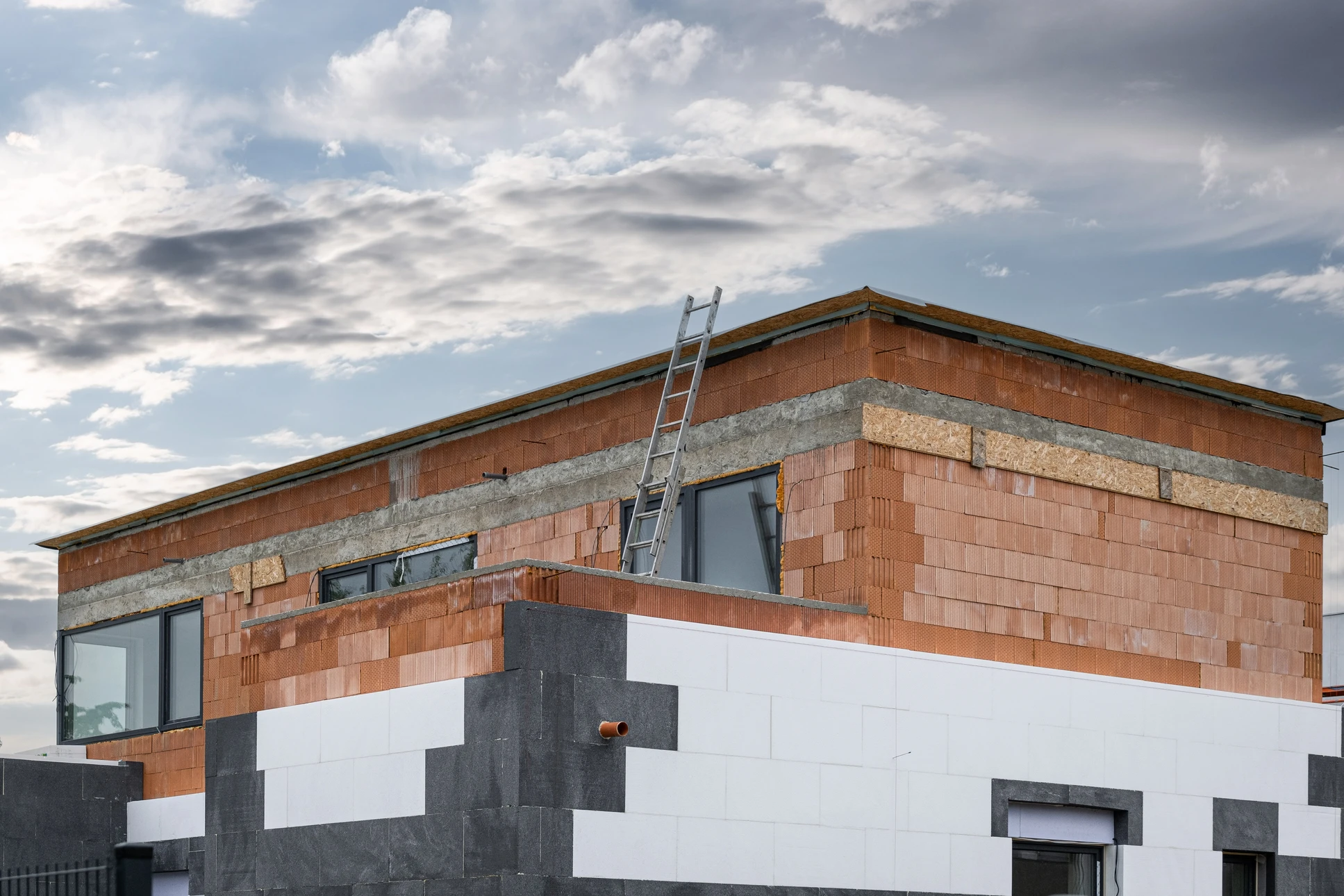 Ouvrier de construction installant des feuilles d'isolation en polystyrène et des espaces de remplissage entre l'installation de mousse d'expansion sur la façade de la maison pour la protection thermique
